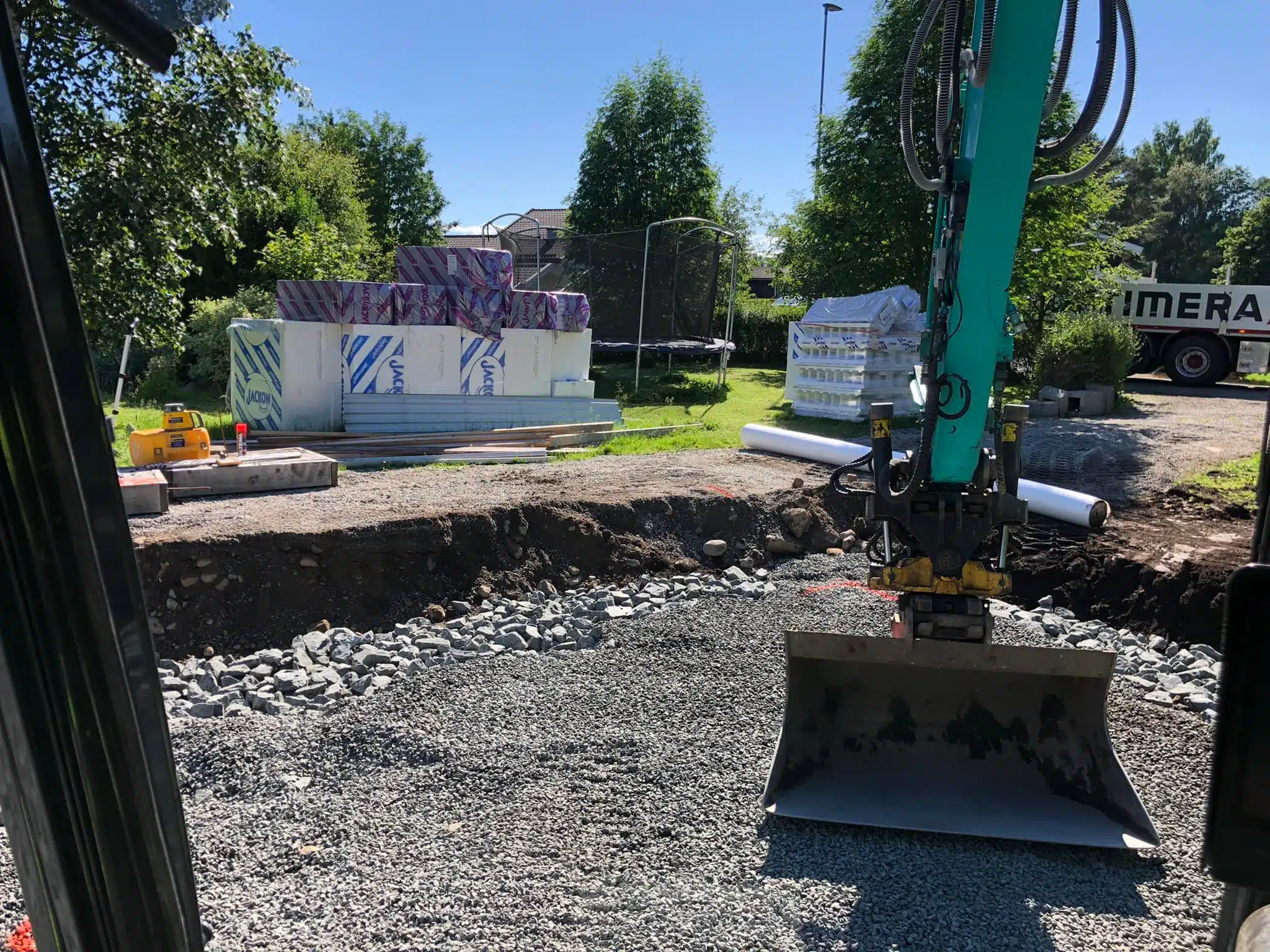 Gravemaskin jobber med å grave rundt gårdsplass