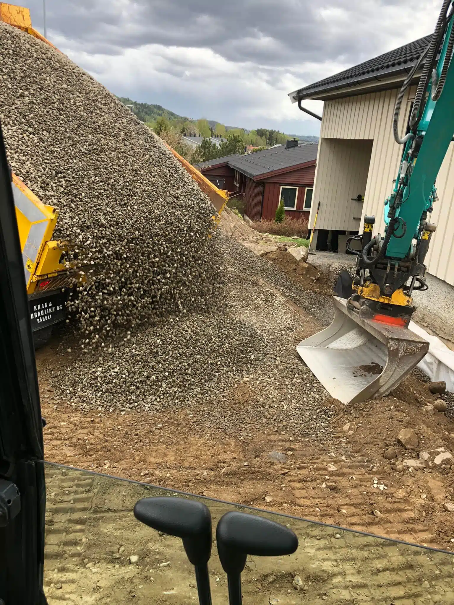 Gravemaskin og lastebil som tømmer grus